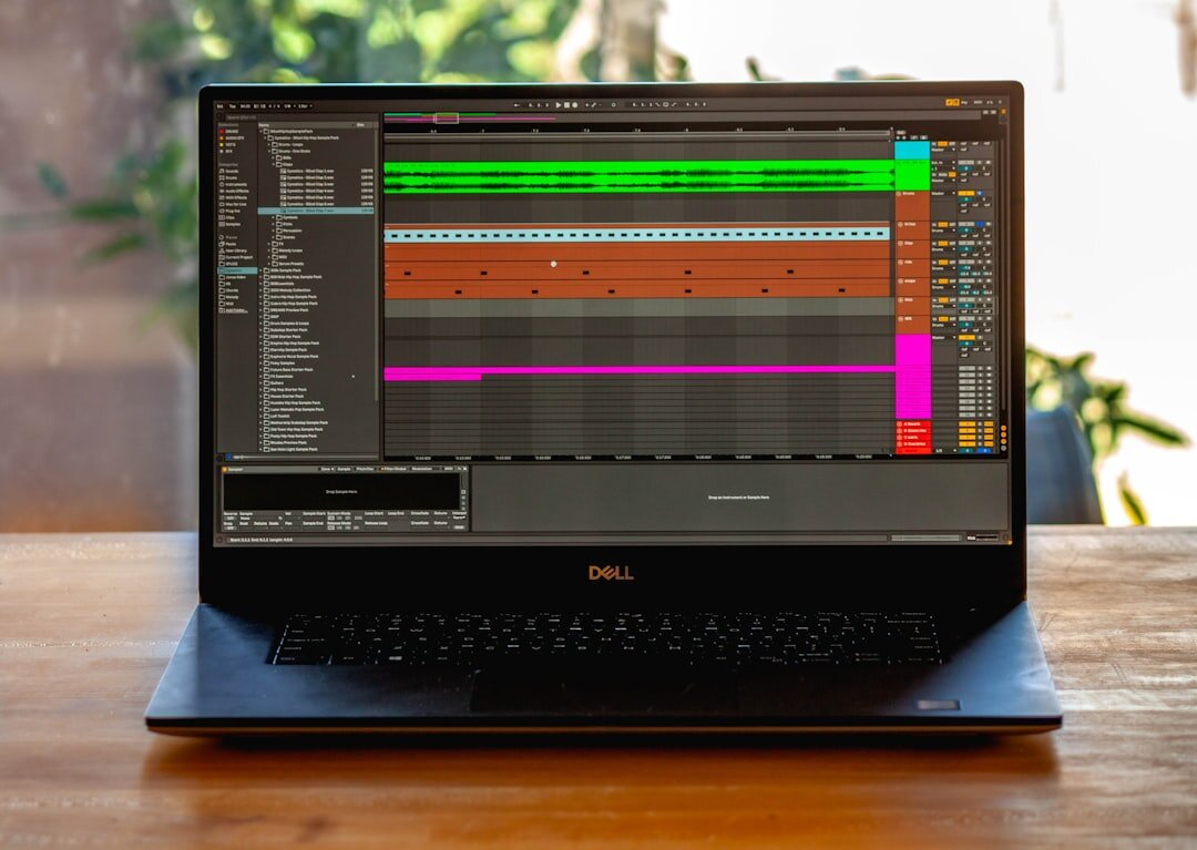 Laptop screen showing an audio editing timeline with sound waveforms, headphones resting beside it